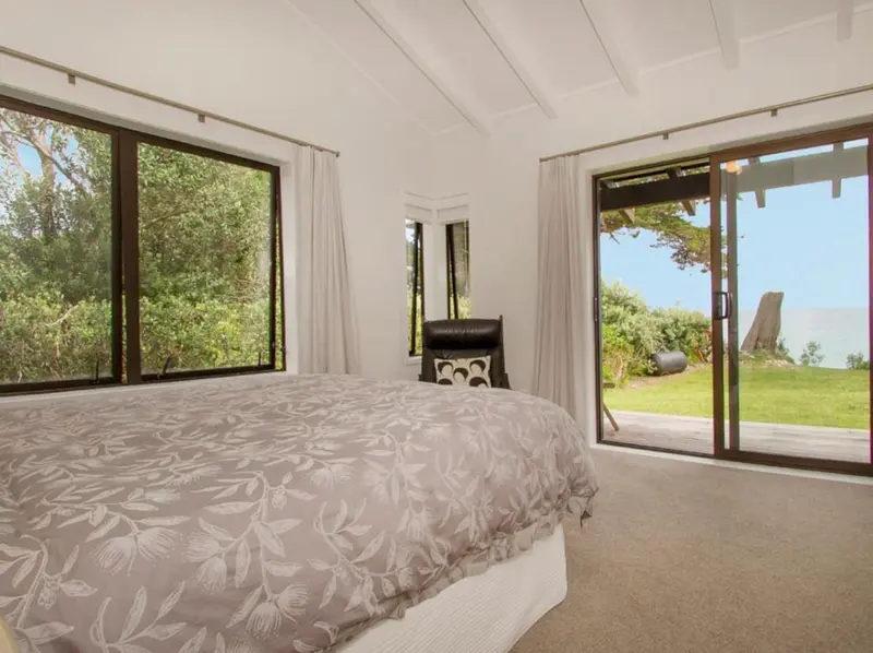 Bedroom with a sliding door opening onto the lawn, with the sea beyond