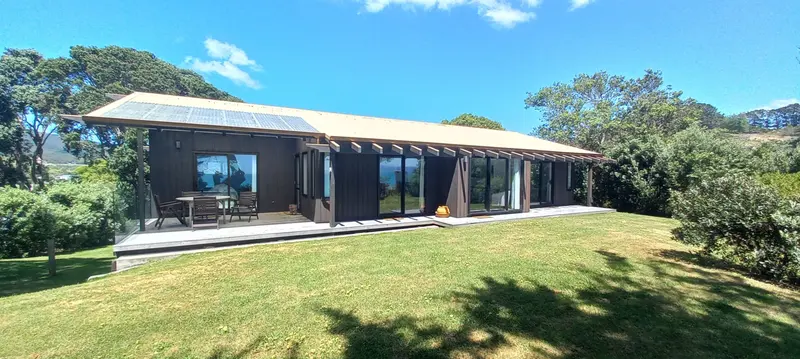 The single-level house with its deck and sliding doors opening onto a flat lawn