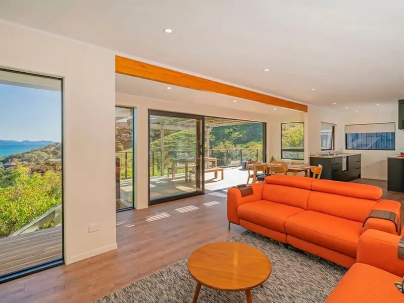 Lounge with orange sofas and floor-to-ceiling windows looking out to the sea