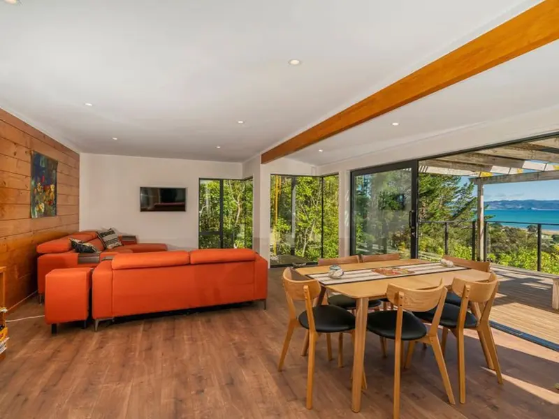 Open-plan living and dining area opening onto the deck, with a sea view