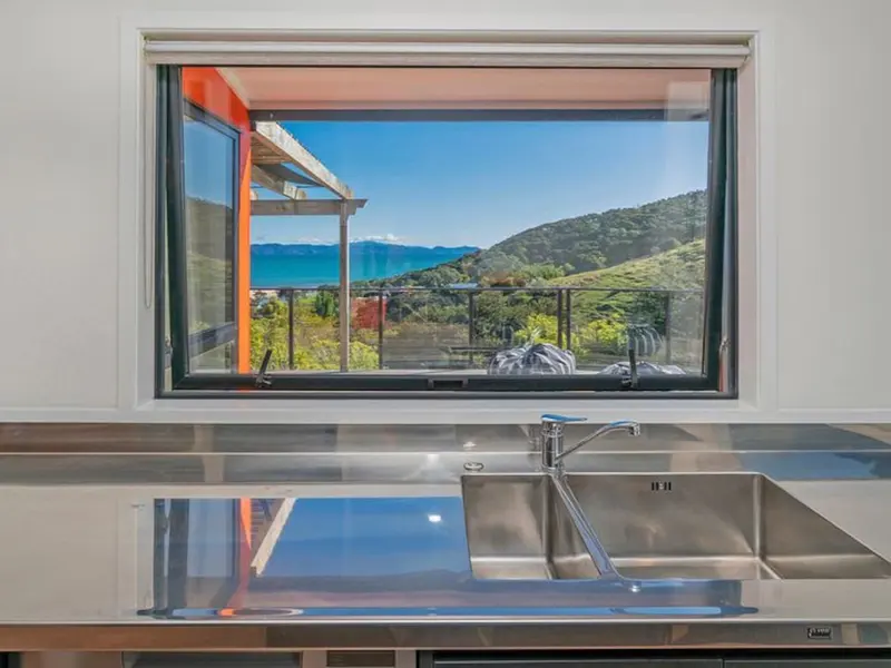 The sea and hills framed by the kitchen window above the sink