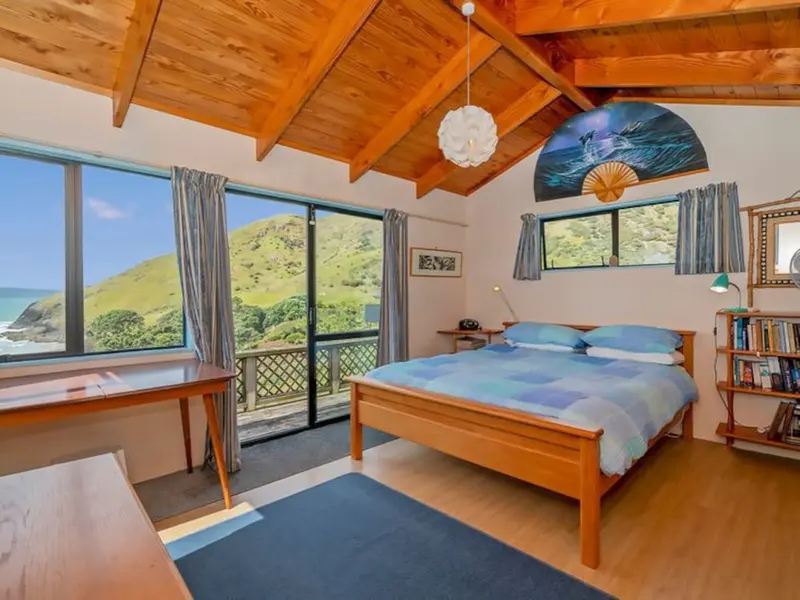 Bedroom with a timber ceiling, a queen bed and a door to a balcony with sea views