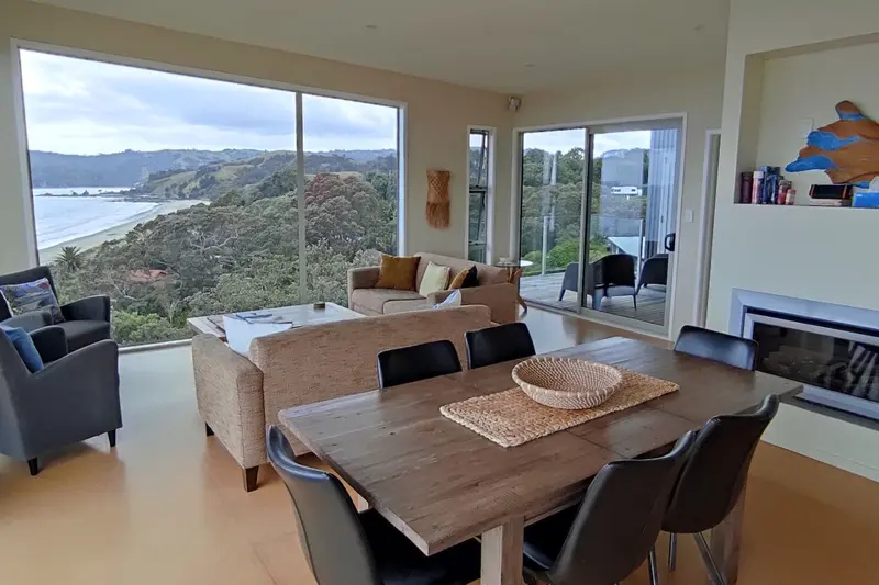 Living and dining room with a large picture window over the beach and headland